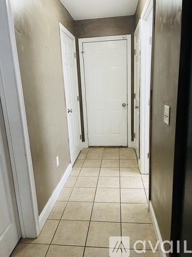 A hallway with a white door and tiled floor.