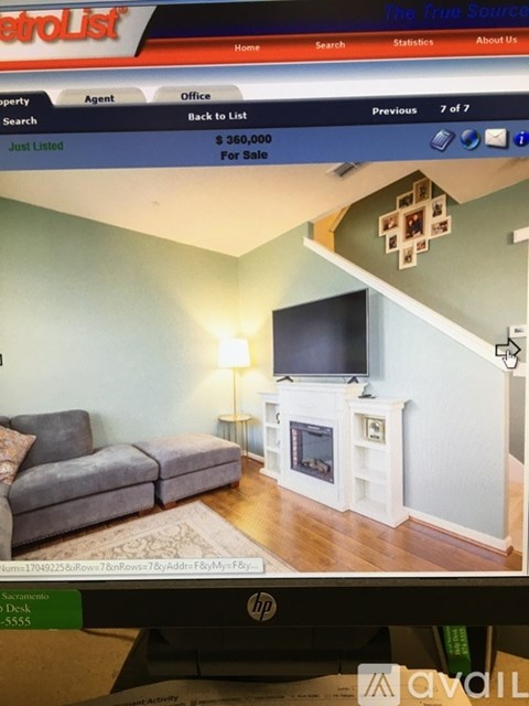 A living room with a grey couch and a white entertainment center.