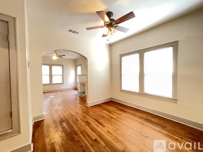 A room with a ceiling fan and wooden flooring.