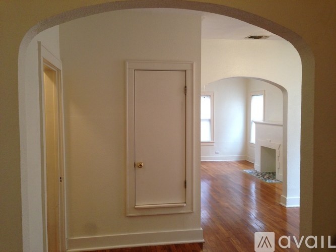 A white door in a room with wooden floors and arched doorways.