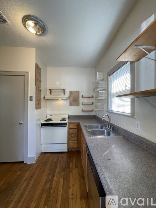 A kitchen with a white oven and wooden floors.