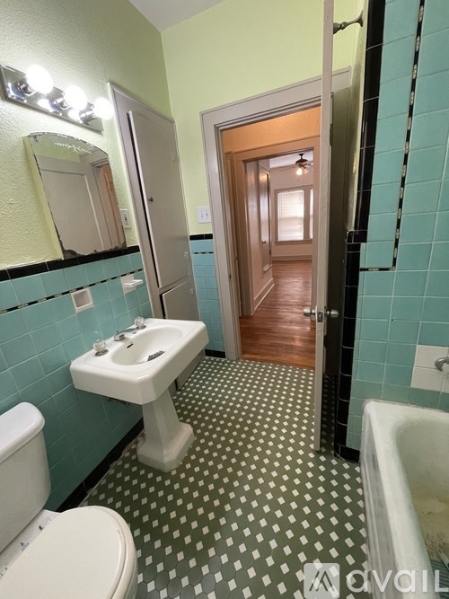 A bathroom with a white sink and green tiles.