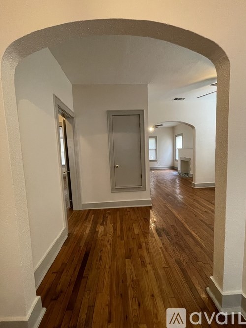 A hallway with wooden floors and white walls.