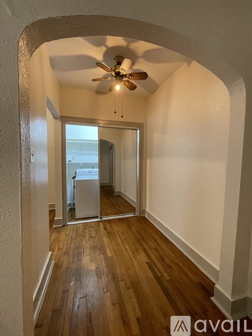 A hallway with a fan and wooden floors.