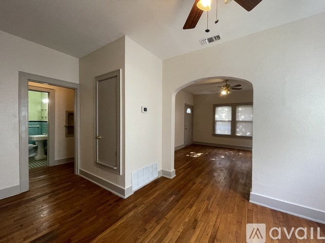A spacious room with wooden floors and a ceiling fan.