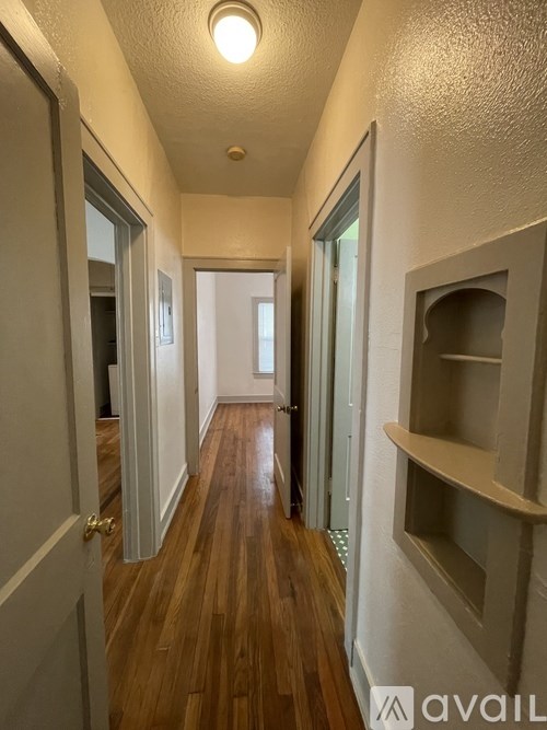 A hallway with wood floors and white walls.