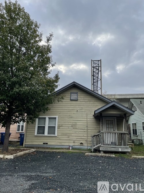 A house with a gravel driveway and a tree in front.