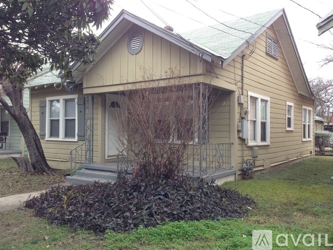 A small house with a green roof and a tree in front.