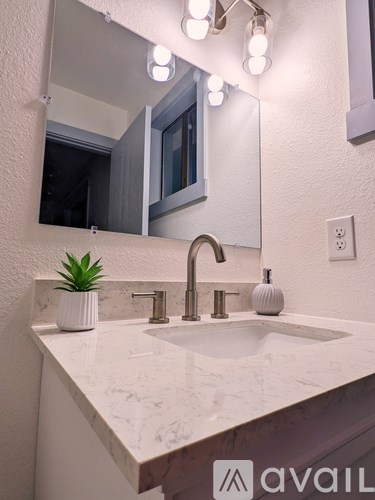 A bathroom sink with a marble countertop and a mirror above it.