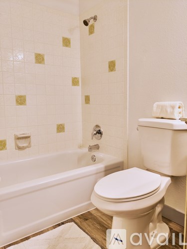 A white toilet sits next to a white bathtub in a bathroom.
