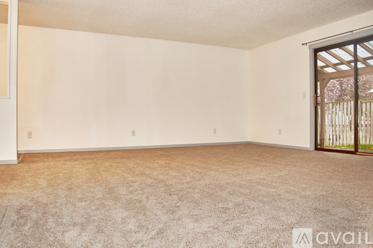 A room with a carpeted floor and a door leading outside.
