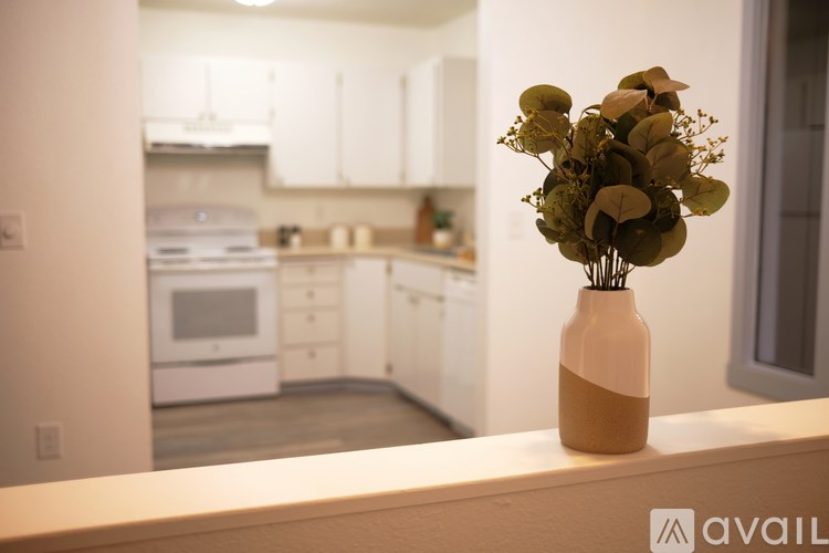 A vase with dried flowers sits on a countertop in a kitchen.