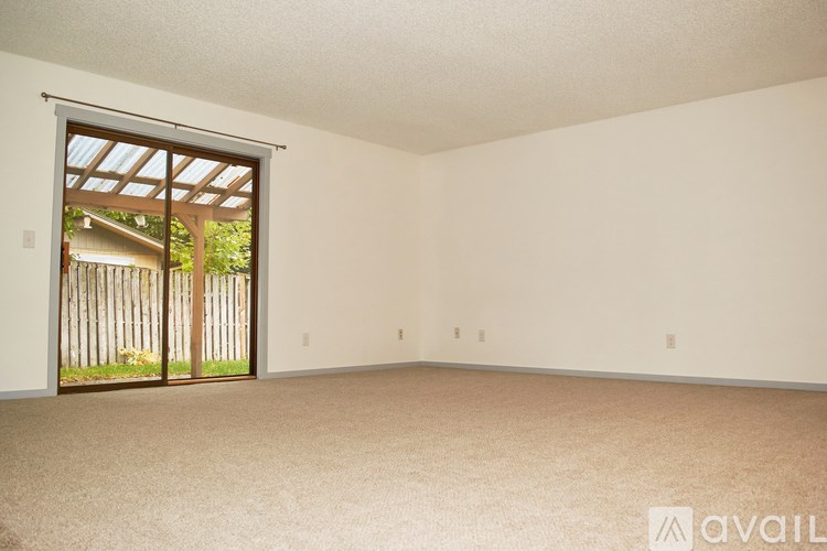 A room with a carpeted floor and a sliding glass door leading to a backyard.