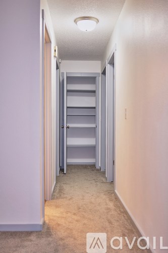 A hallway with a carpeted floor and a set of stairs leading to a second floor.