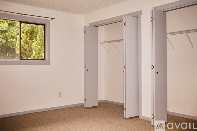 A room with a window and two open closet doors.
