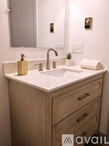 A bathroom vanity with a sink, mirror, and towel.