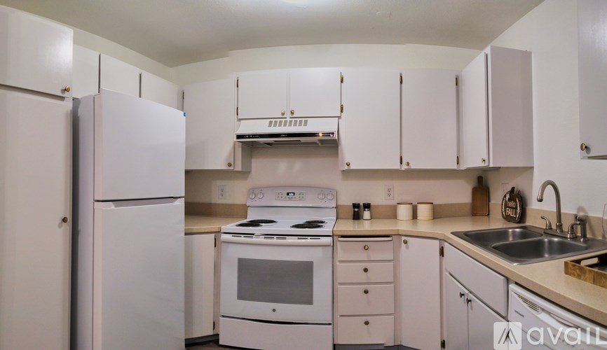 A white kitchen with a refrigerator, oven, and sink.