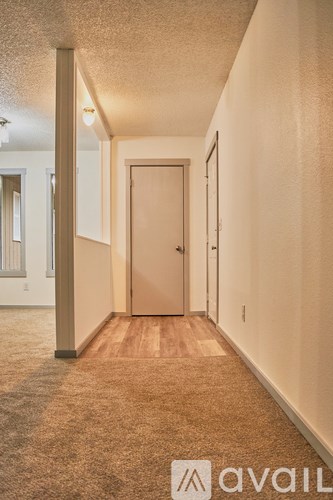 A hallway with a carpeted floor and a door at the end.