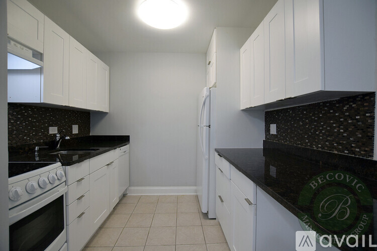 A kitchen with white cabinets and black countertops.