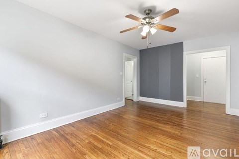 A room with a ceiling fan and wooden flooring.
