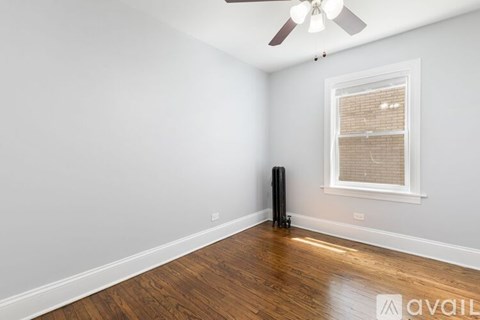 A room with a ceiling fan, a window with blinds, and a wooden floor.