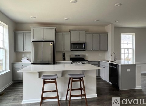 A kitchen with a white island and wooden bar stools.