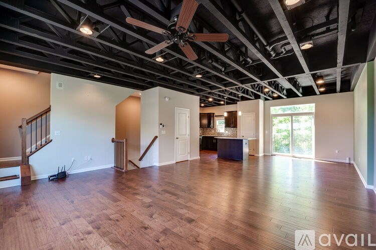 A spacious room with wood flooring and a ceiling fan.
