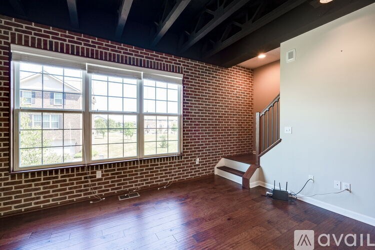 A room with a brick wall and wooden flooring is available for rent.