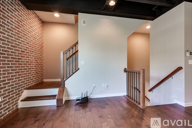 A room with a brick wall and wooden stairs.