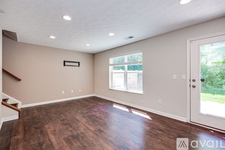 A room with wooden floors and a white door leading outside.