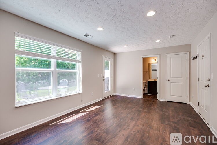 A spacious room with wooden floors and a large window with blinds.