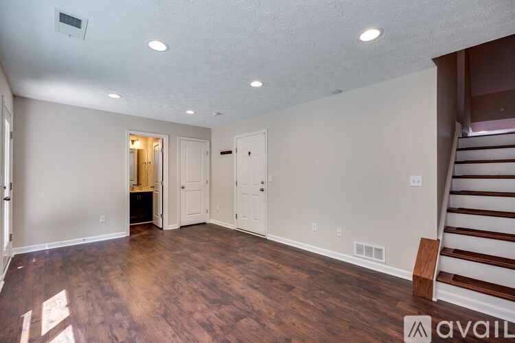 A room with wooden floors and a staircase on the right side.