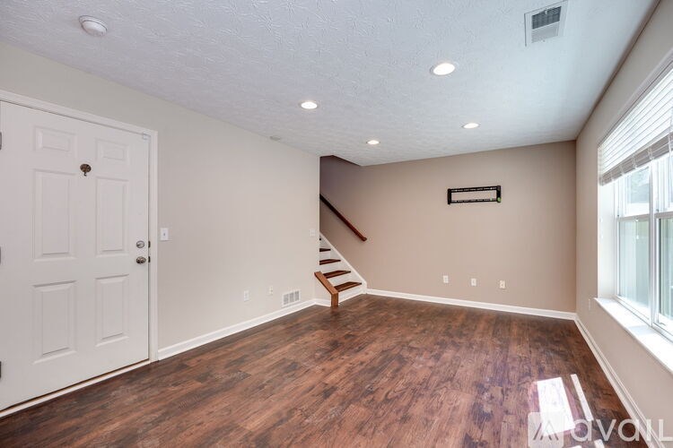 A room with a white door and a wooden staircase.