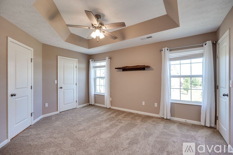 A spacious room with a ceiling fan and carpeted floor.