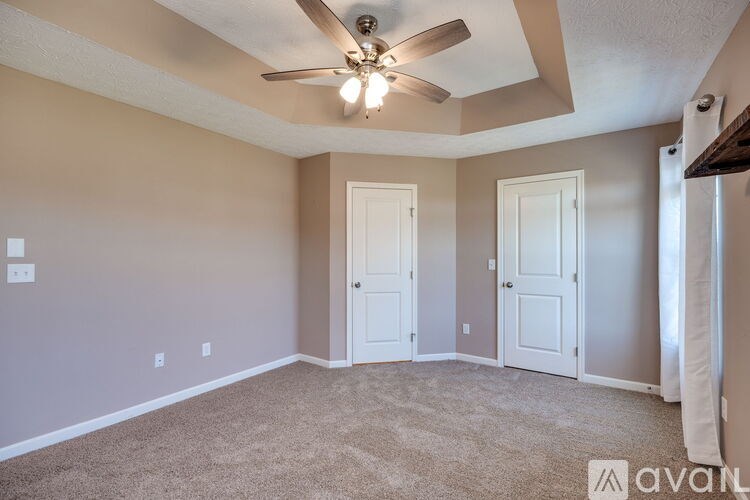 A room with a ceiling fan and two doors.
