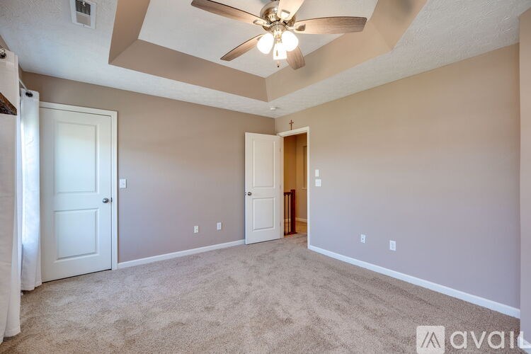 A room with a ceiling fan and carpeted floor.