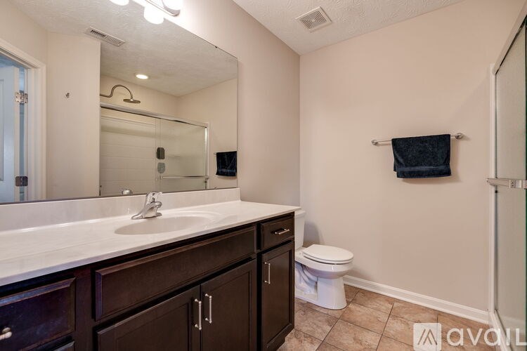 A bathroom with a sink, mirror, toilet, and a towel hanging on the wall.