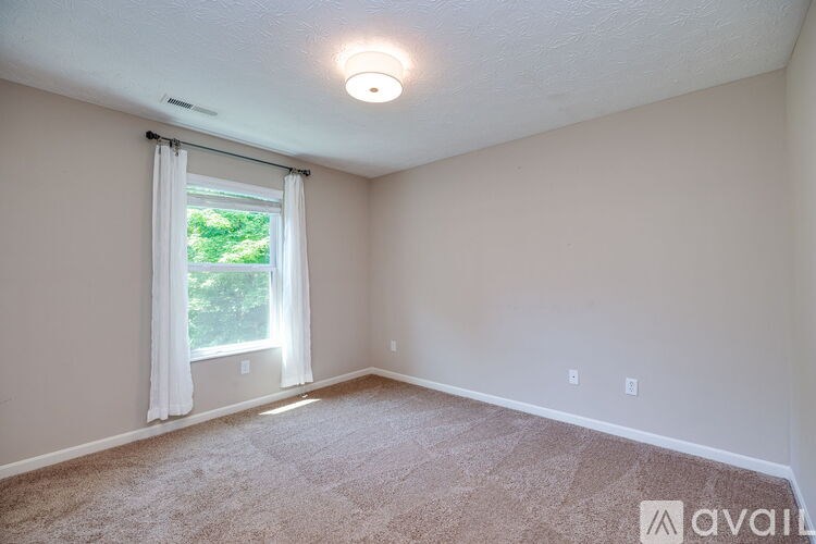A room with a window and carpeted floor.