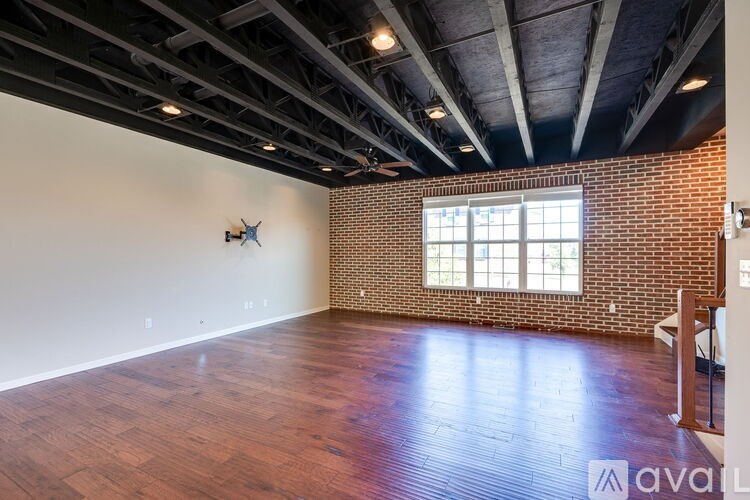 A room with wooden floors and a brick wall with a window.