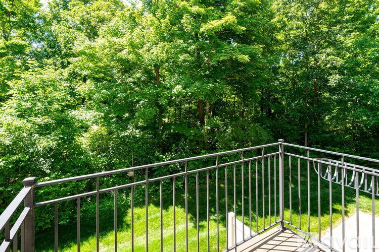 A metal railing overlooks a lush green lawn.