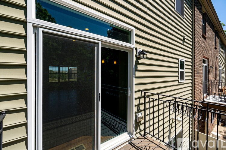 A patio with a glass door and a black metal railing.