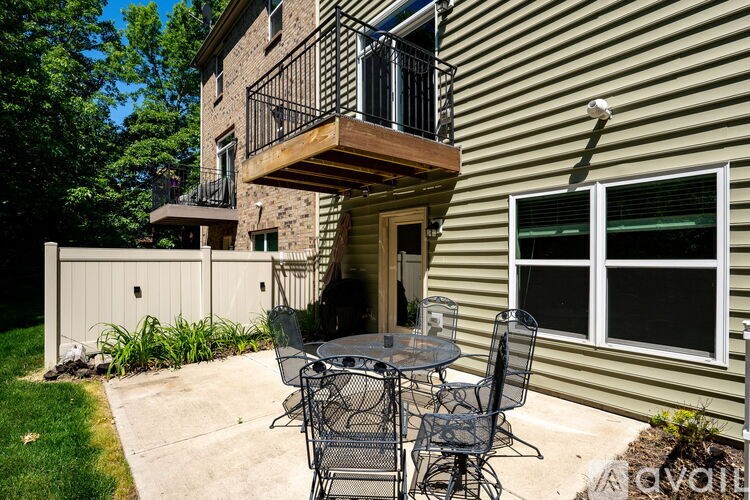 A patio with a table and chairs is in front of a house.