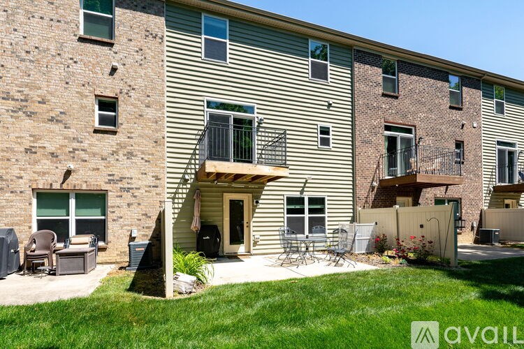 A building with a balcony and a patio with chairs and a grill.