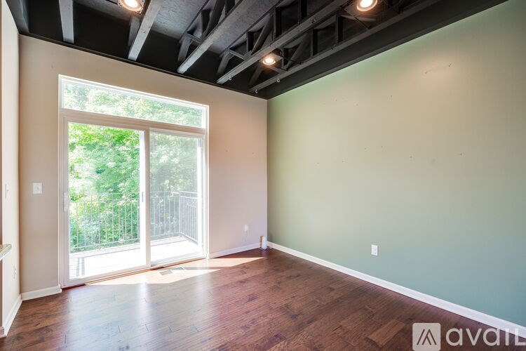 A room with wooden floors and a sliding glass door leading to a balcony.
