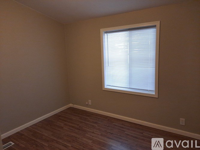 A room with a window and wooden flooring.