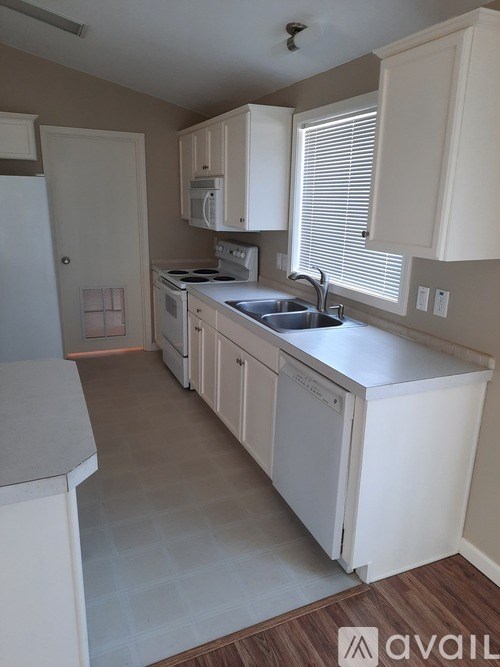 A kitchen with white cabinets and appliances.