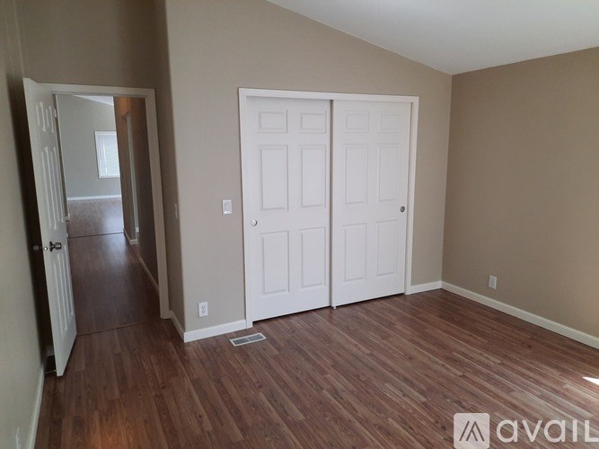 A room with a white door and a brown floor.