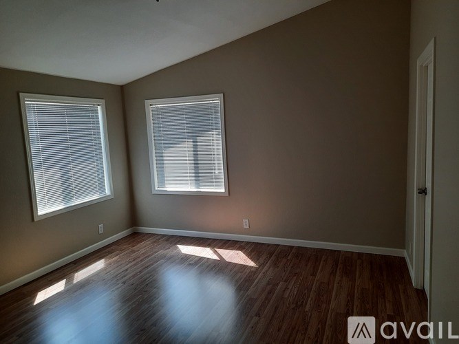 A room with wooden floors and two windows.