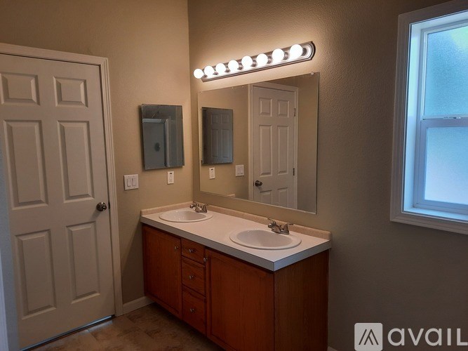 A bathroom with a white sink and a mirror with lights on it.