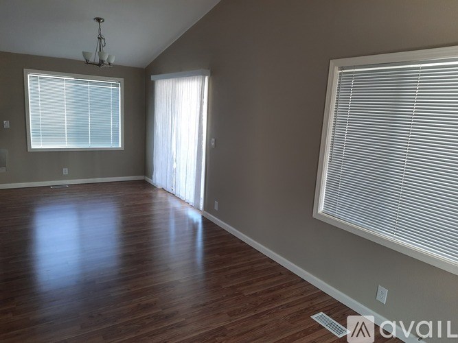 A room with wooden floors and a window with blinds.